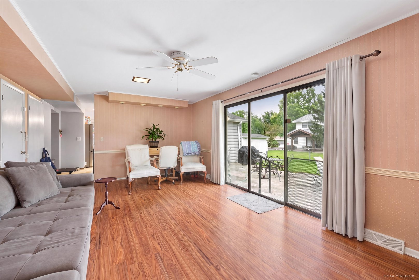 Living and dining area with wood-look floors and sliding doors opening to a patio and fenced yard.