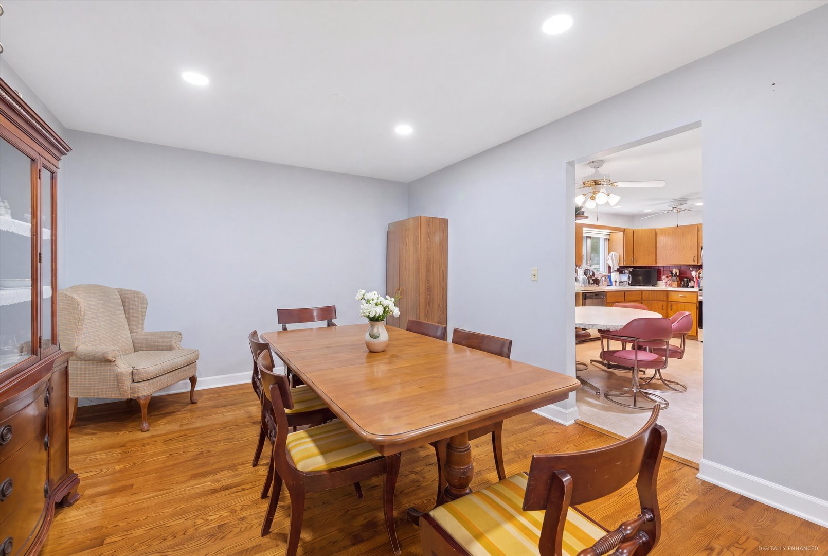 Dining room with a wooden table and chairs, hardwood floors, and the kitchen visible through the doorway.