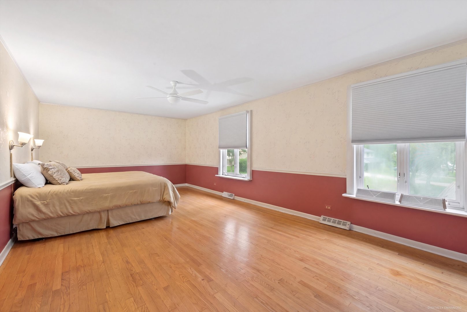 Bedroom with hardwood floors, a bed, and two windows with blinds.