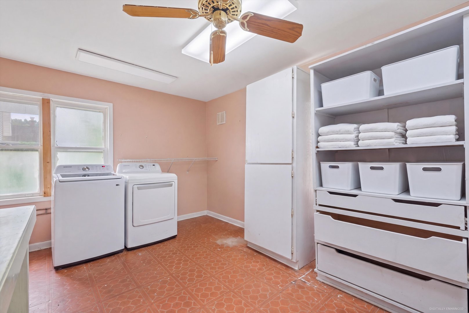 Laundry room with washer and dryer, large storage shelves, folded towels, and white bins.