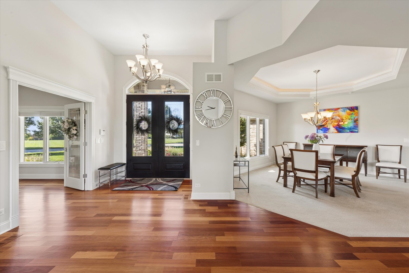 Bright foyer with dark double entry doors, hardwood floors, and an adjoining formal dining room.
