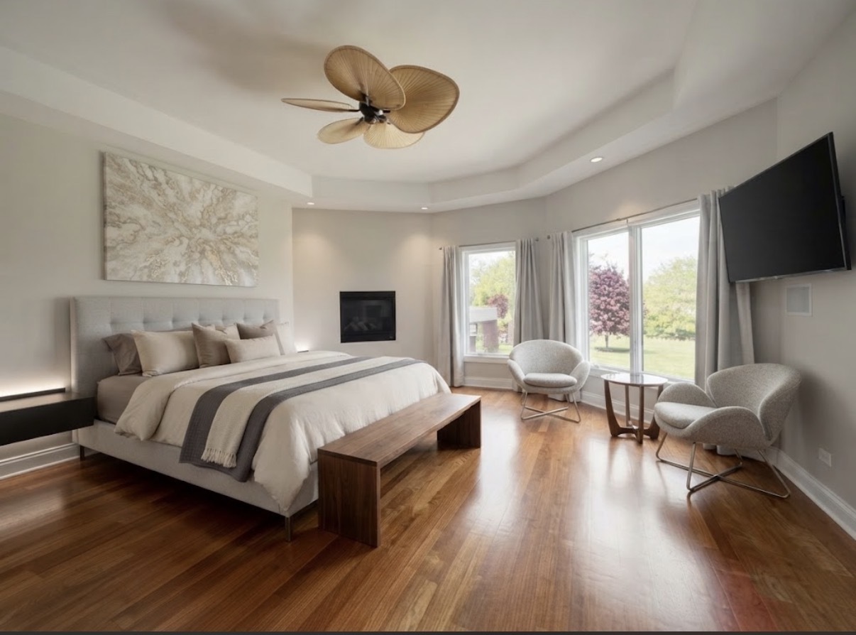 Primary bedroom with a large upholstered bed, hardwood floors, and a window-side sitting area.