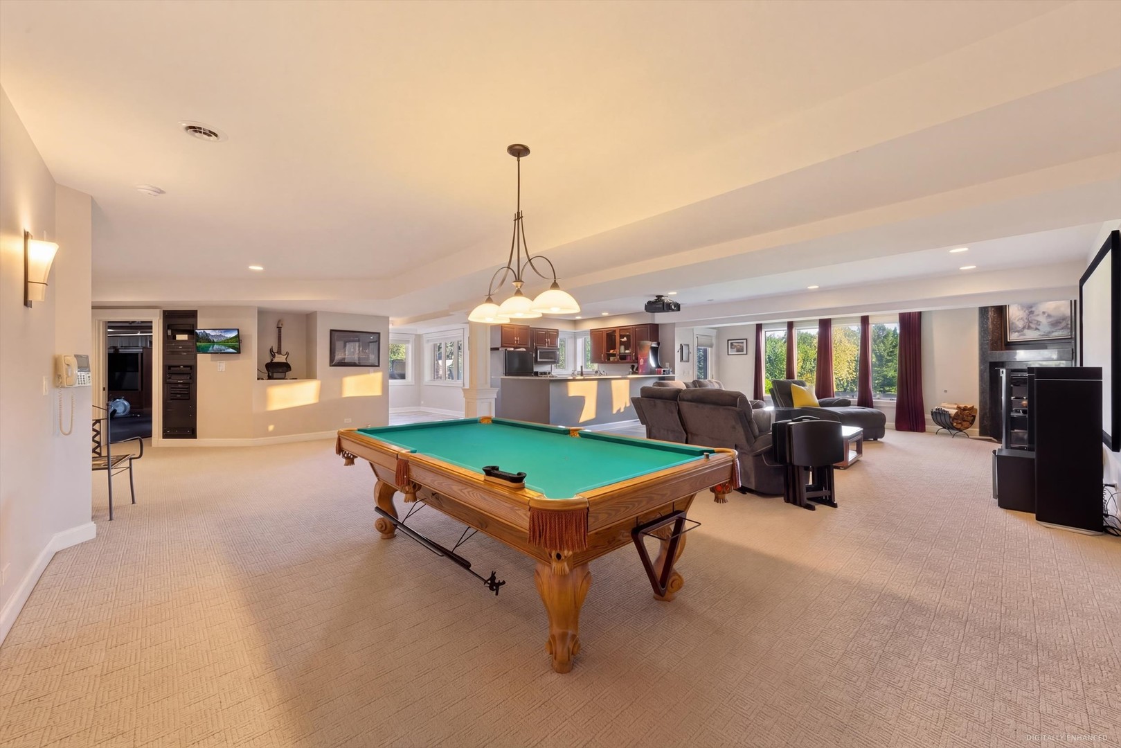 Furnished recreation room with a green-felt pool table, lounge seating, large windows, and a kitchenette.