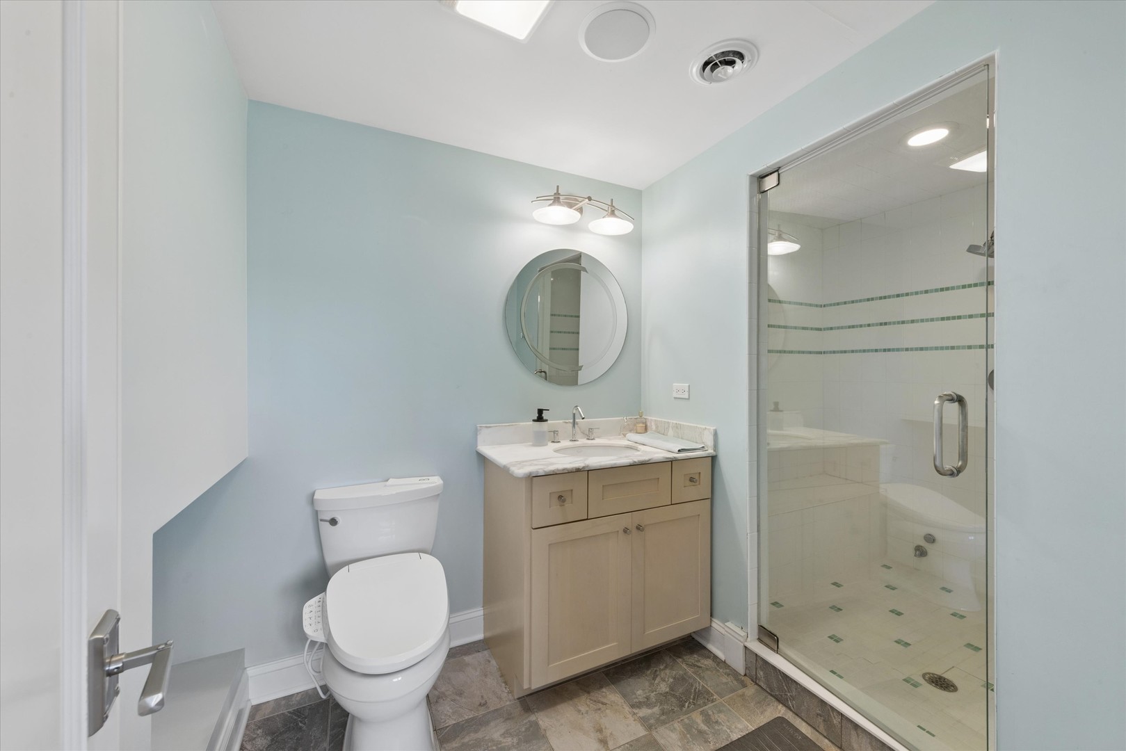 Bathroom with a marble-topped vanity, bidet-style toilet, and glass walk-in shower.