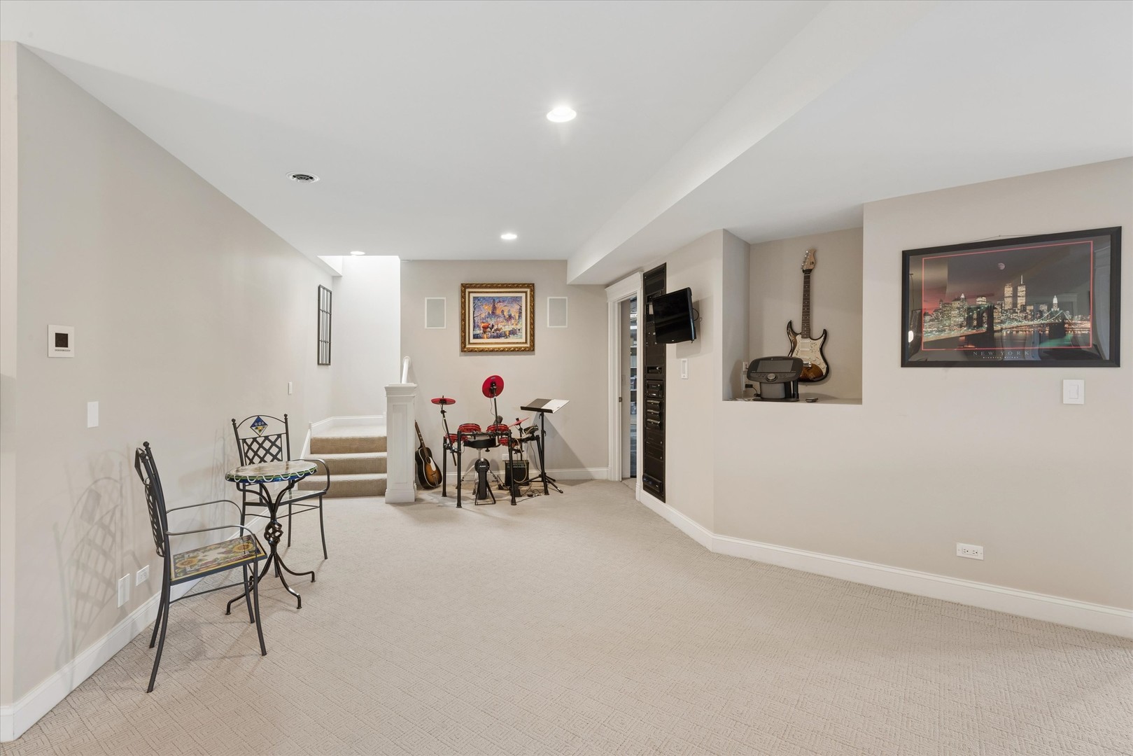 Finished basement recreation room with electronic drums, a guitar, and a small table and chairs.
