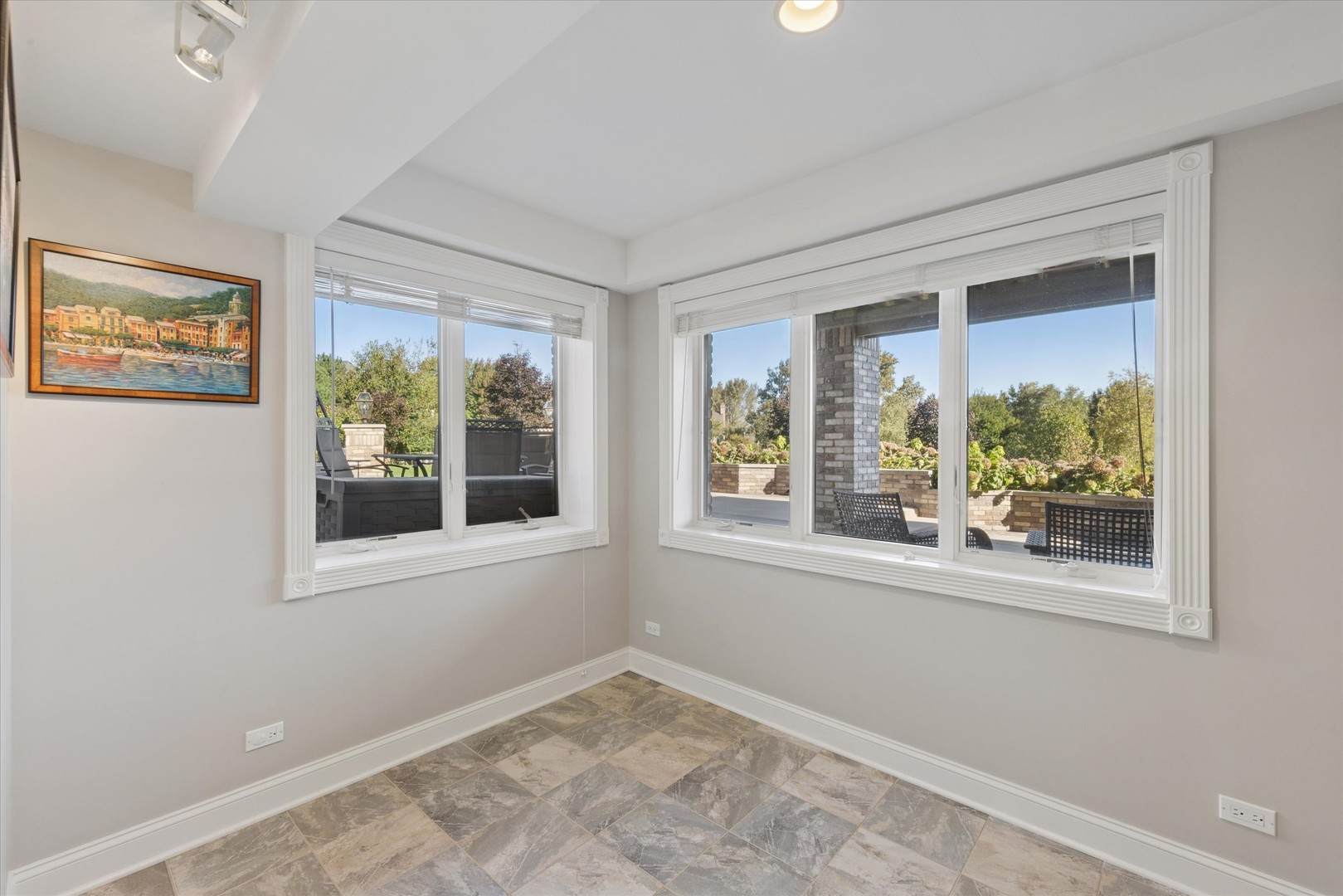 Sunroom with patterned tile flooring and large windows overlooking a landscaped patio.