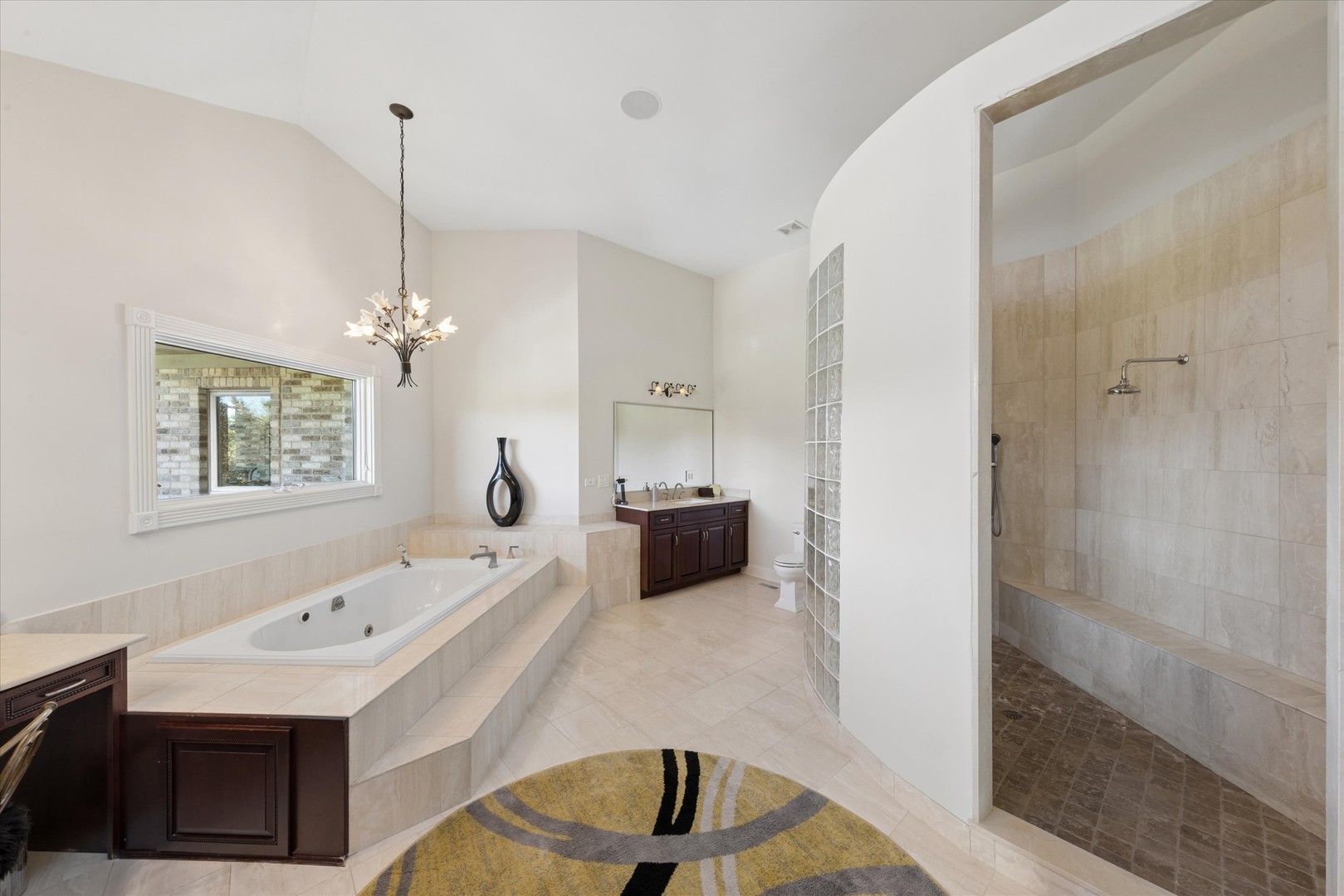 Primary bathroom with a built-in soaking tub, dark wood vanity, and tiled walk-in shower with bench.
