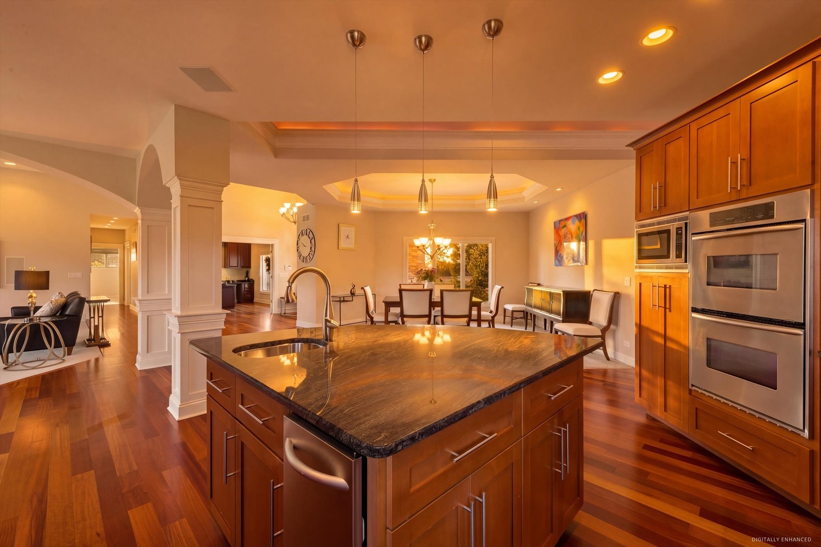 Spacious kitchen with a large stone island, rich wood cabinets, and stainless steel double ovens.