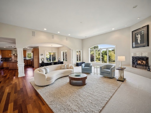 Living room with a curved white sofa, blue armchairs, arched windows, and a fireplace.