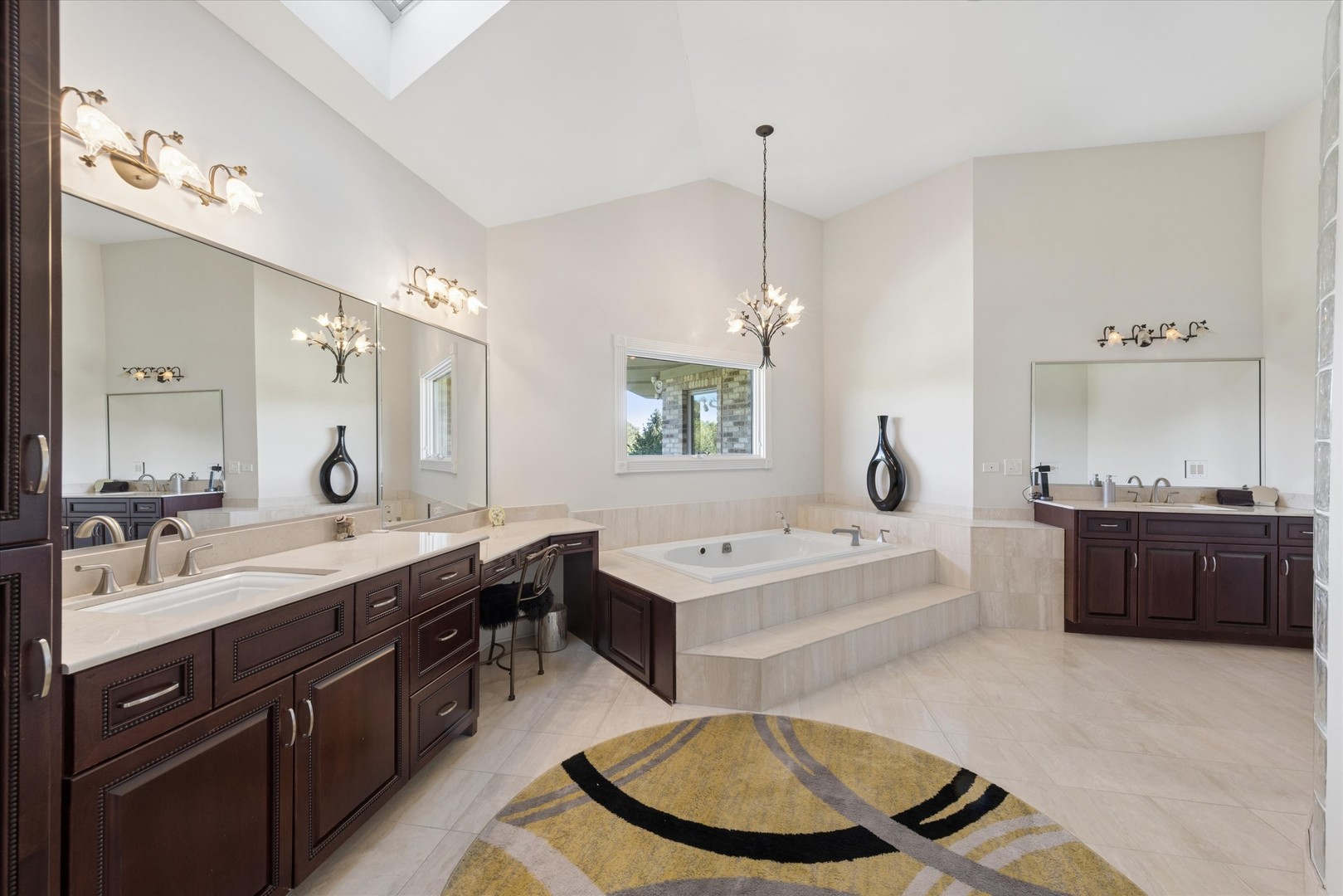 Spacious bathroom with dual dark wood vanities and a raised soaking tub beneath a vaulted ceiling.