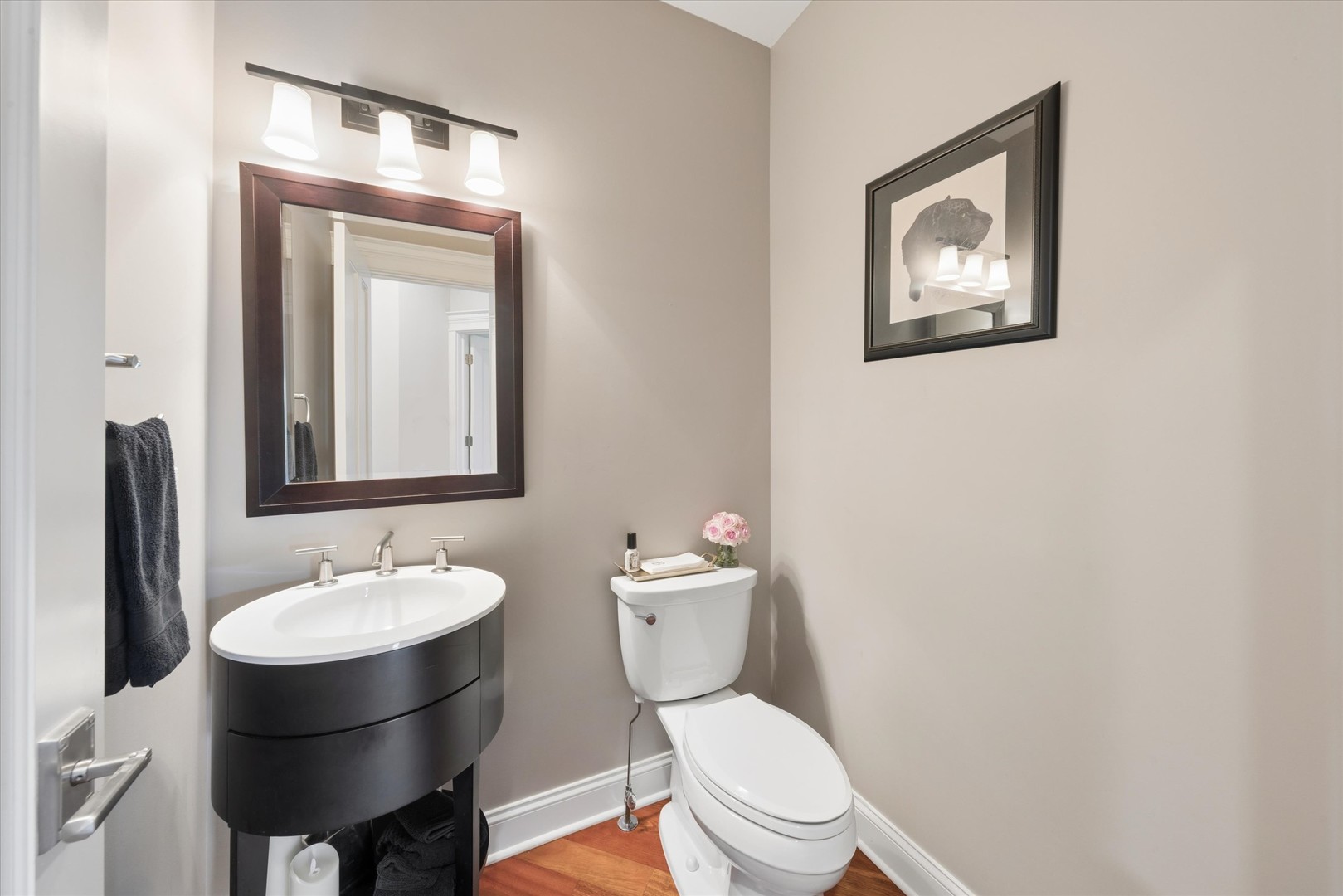 Bathroom with a dark curved vanity, white sink, large mirror, and toilet.