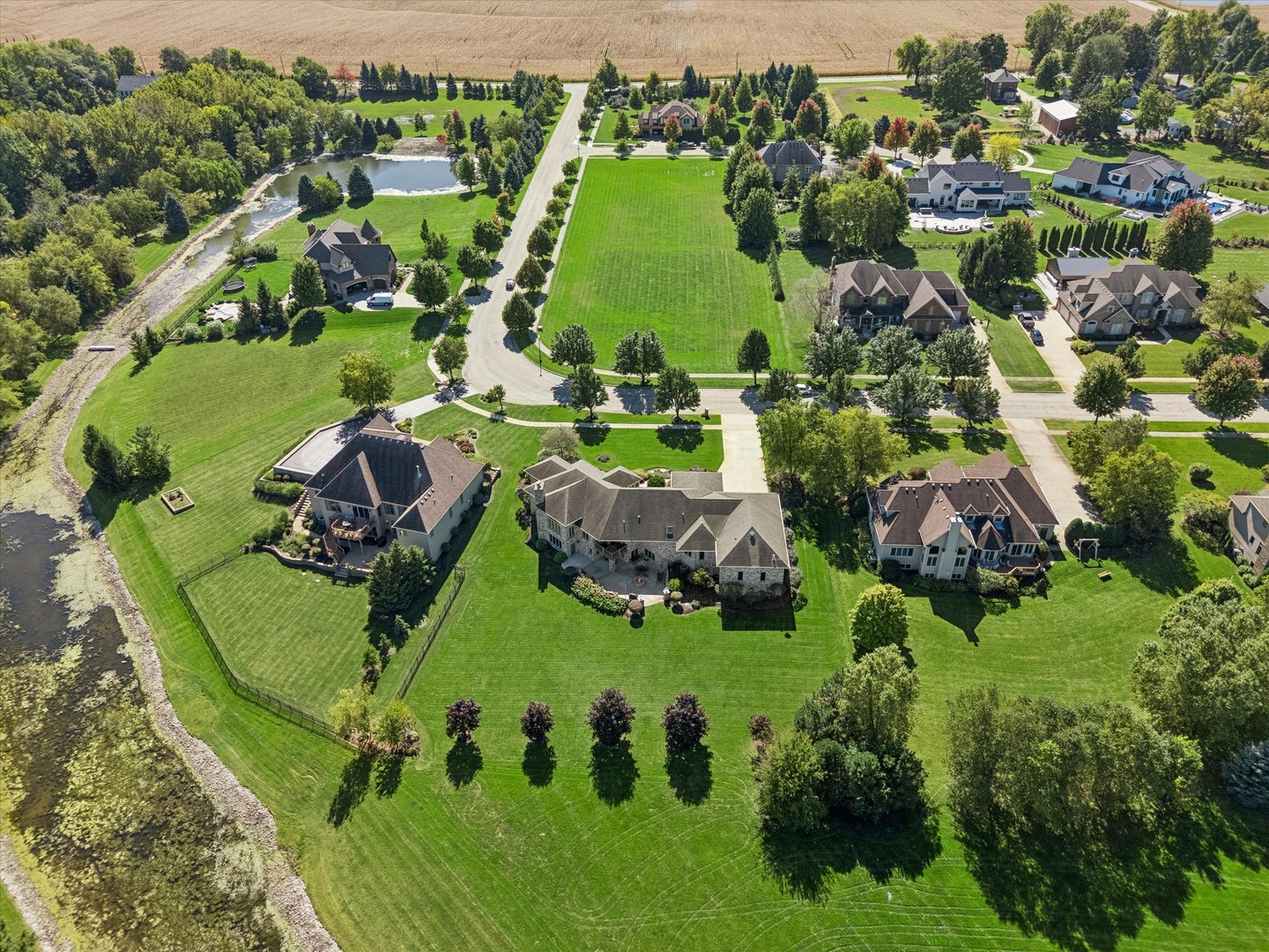 Aerial view of spacious homes and lawns beside a pond and winding creek.