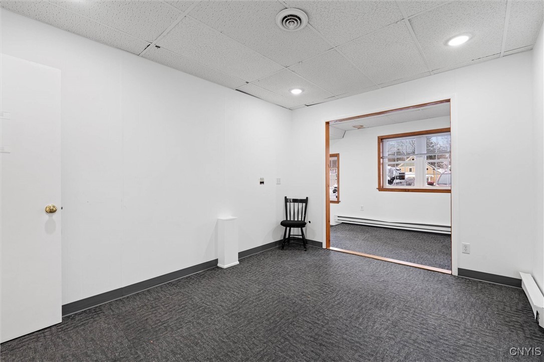 Empty carpeted office with a chair and wood-trimmed opening to a windowed room.