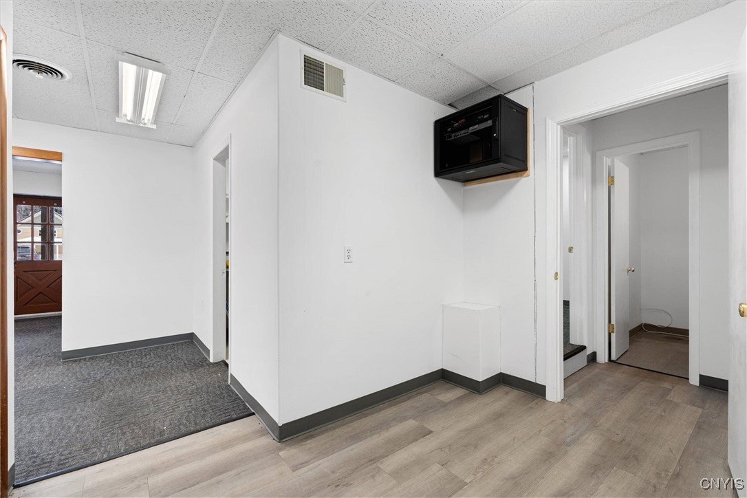 Commercial interior hallway with light wood-look flooring, carpeted area, and multiple doorways.