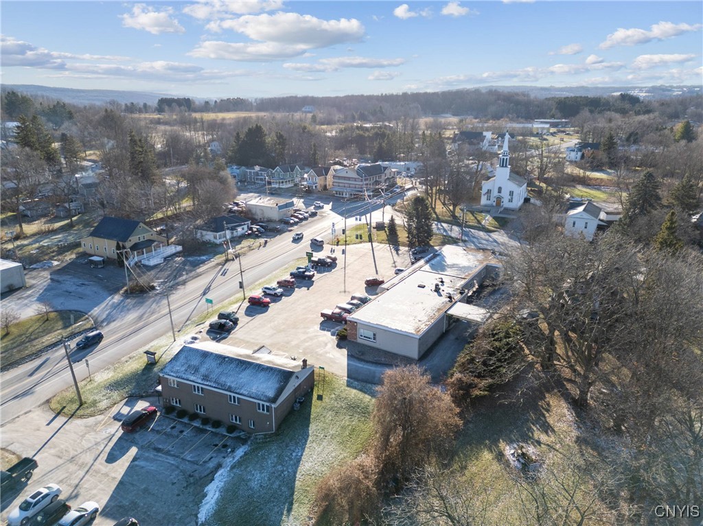 Aerial view of a flat-roofed commercial building and parking lot beside a small-town road.