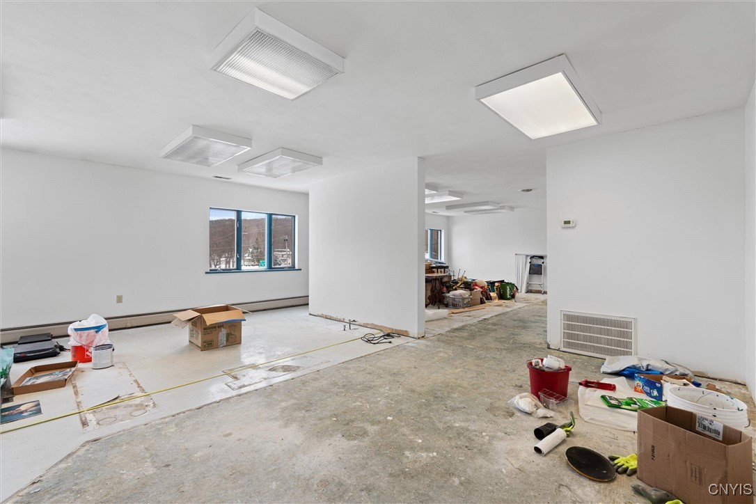 Unfinished interior room with fluorescent lights, concrete flooring, and construction supplies.