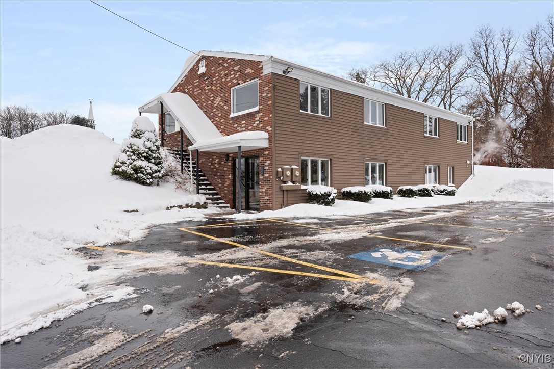 Two-story brick-and-siding building with an exterior staircase and snow-covered parking lot.