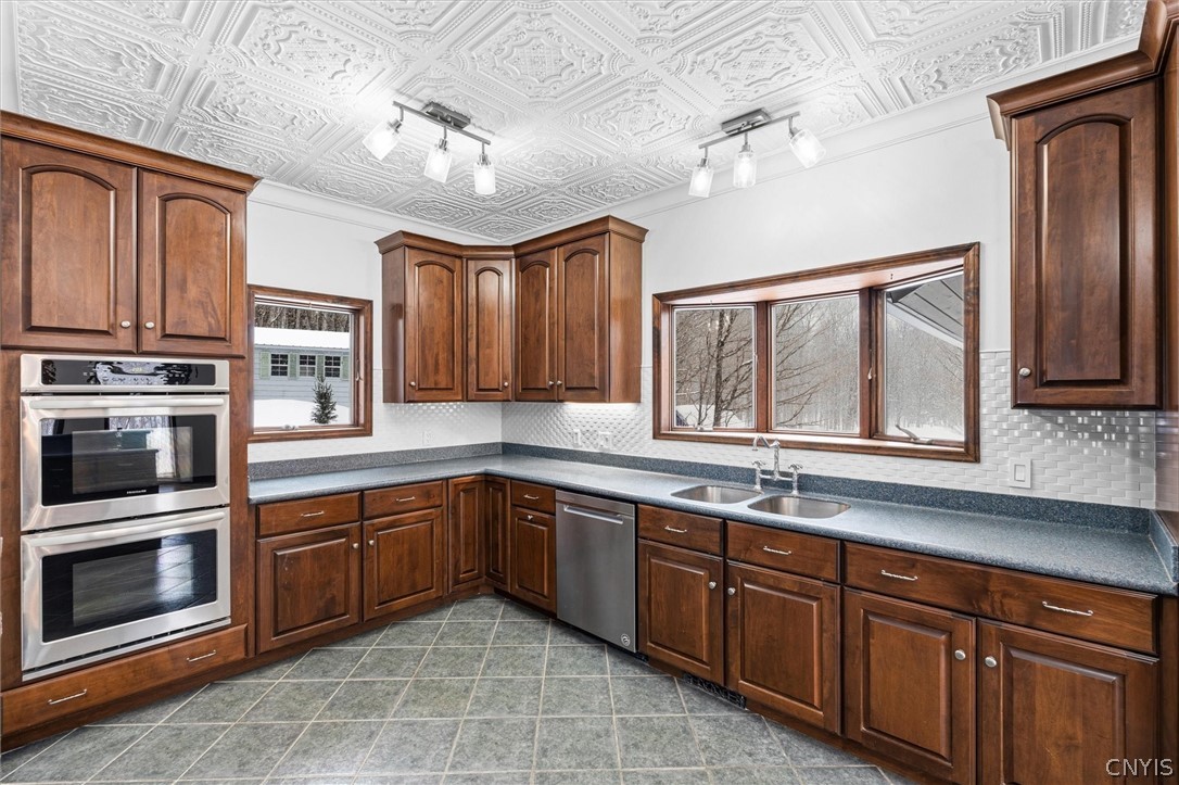 Kitchen with dark wood cabinetry, double wall ovens, gray countertops, and a decorative ceiling.