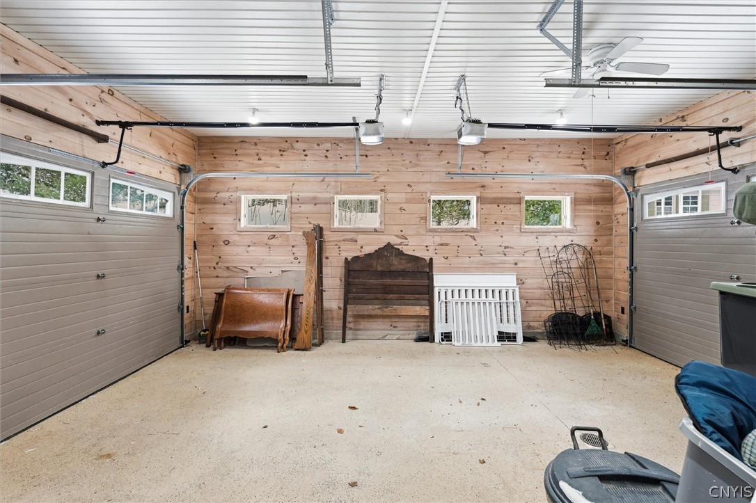 Garage with wood-plank walls, a white paneled ceiling, and stored furniture along the back wall.