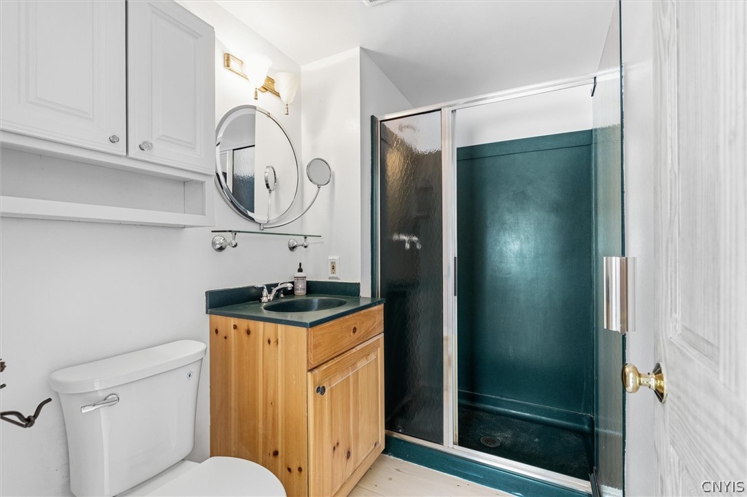 Bathroom with a teal glass-door shower and natural wood vanity.