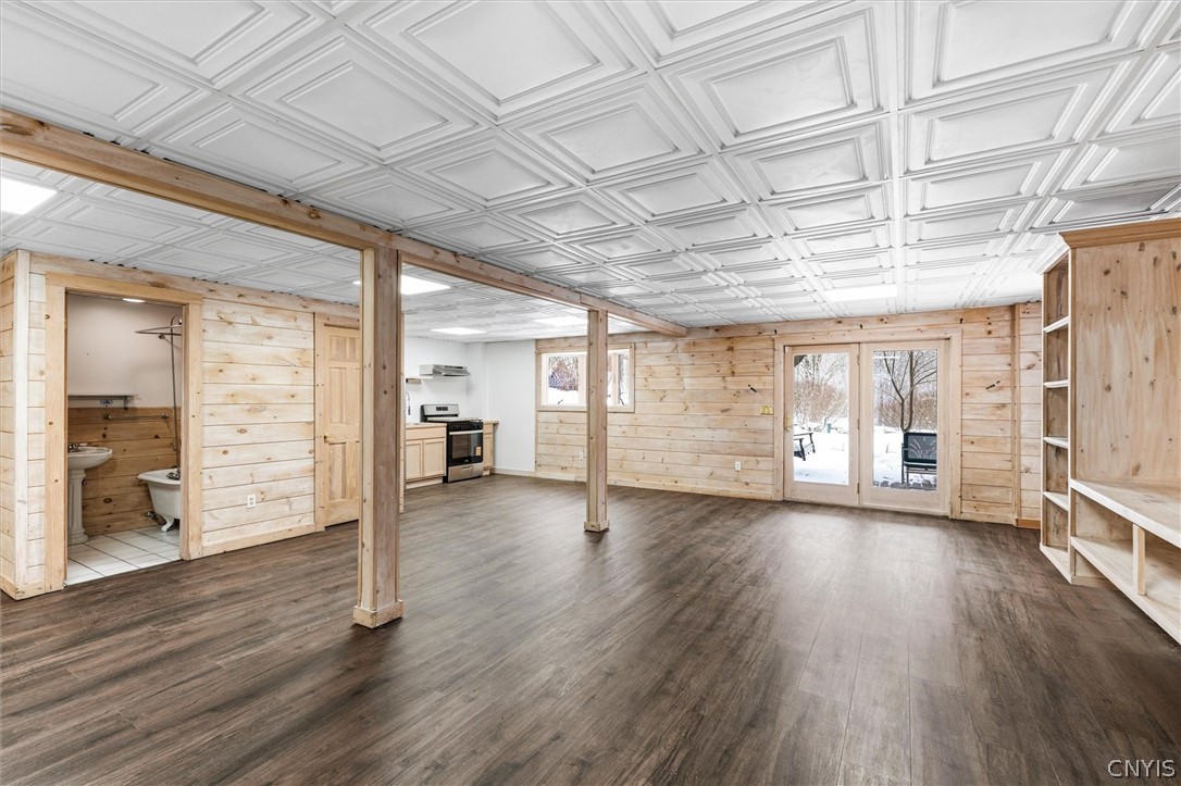 Finished basement with wood-paneled walls, built-in shelves, and glass doors overlooking a snowy yard.