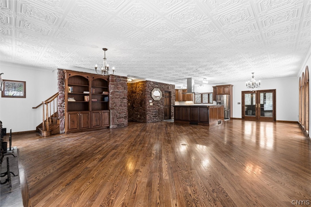 Open living area with hardwood floors, stone wall, built-in bookshelves, and adjoining kitchen.