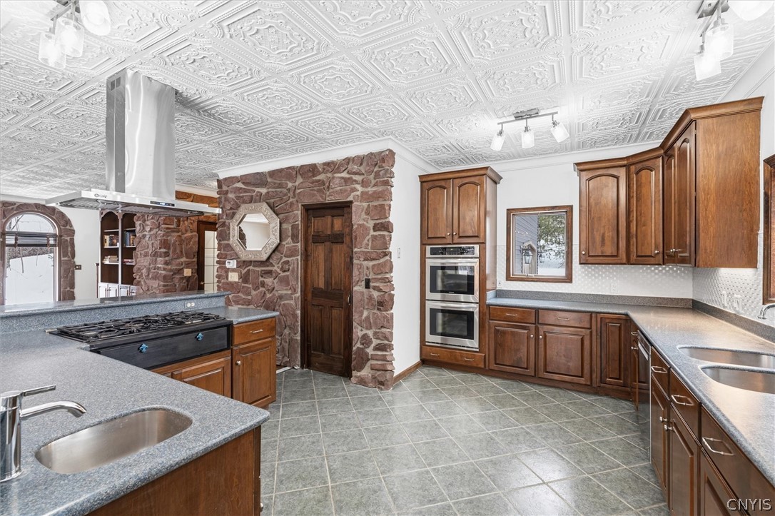 Kitchen with dark wood cabinetry, double wall ovens, and a stone accent wall.