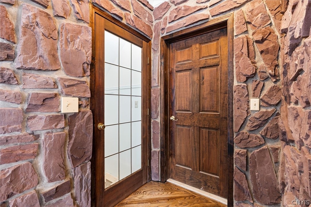 Stone-walled entryway with a glazed wood door beside a solid paneled door.
