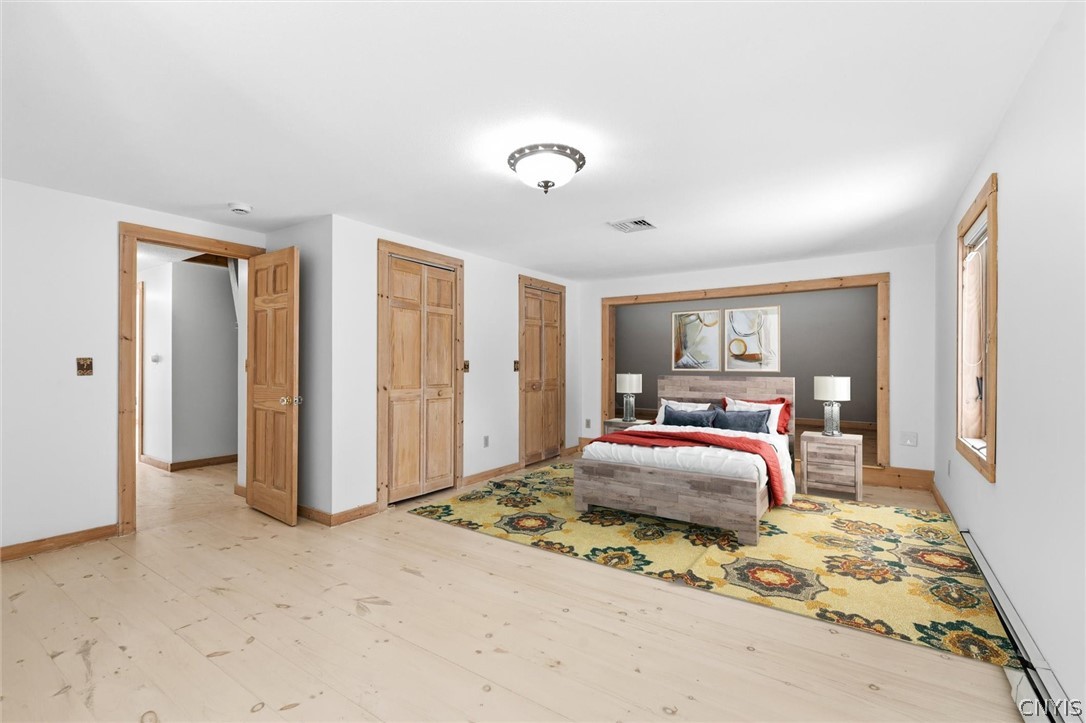 Staged bedroom with a colorful floral rug, pale wood floors, and natural wood trim.