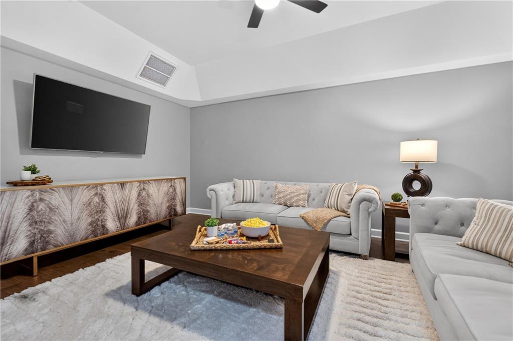 Furnished living room with gray tufted sofas, dark coffee table, and wall-mounted television.