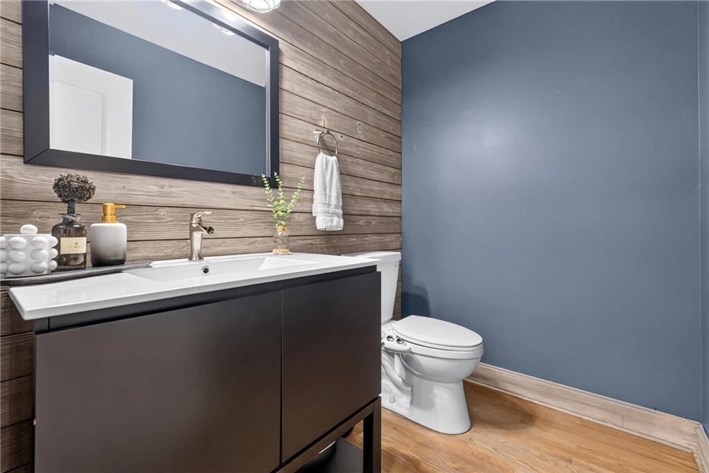 Bathroom with a dark floating vanity, double sink, wood-plank accent wall, and blue wall beside the toilet.