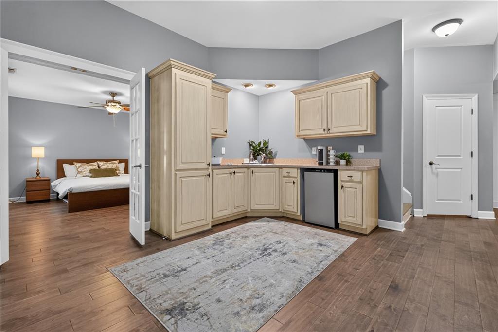 Kitchenette with light wood cabinets and compact dishwasher beside an adjoining bedroom.