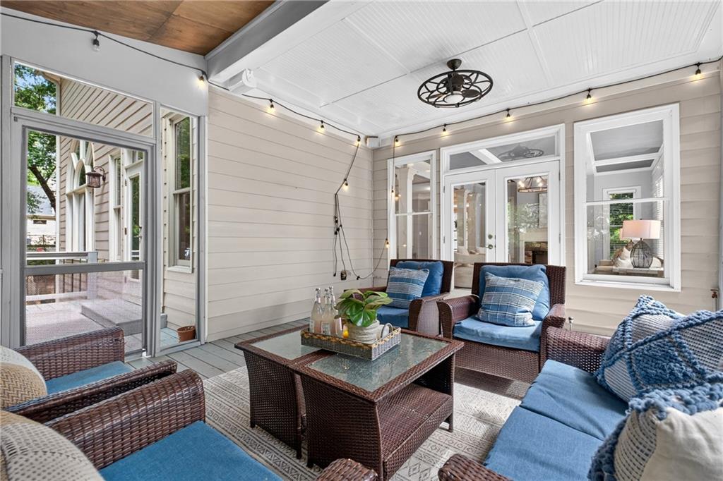 Furnished sunroom with wicker seating, blue cushions, and a glass-top coffee table.