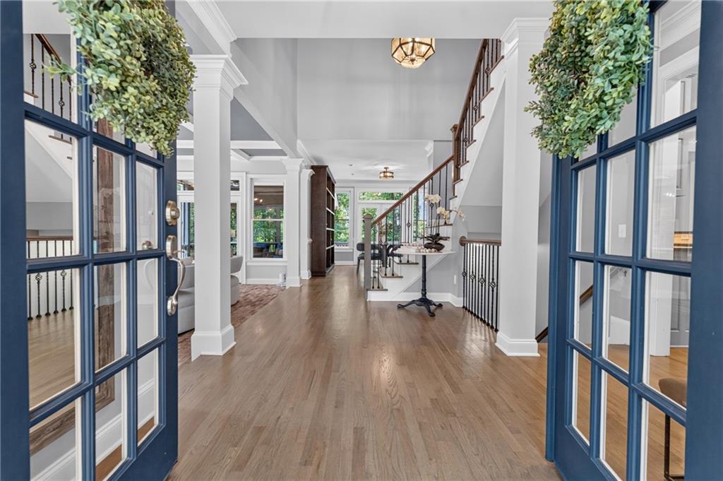 Foyer with hardwood floors, blue-framed glass doors, and a staircase with dark railings.