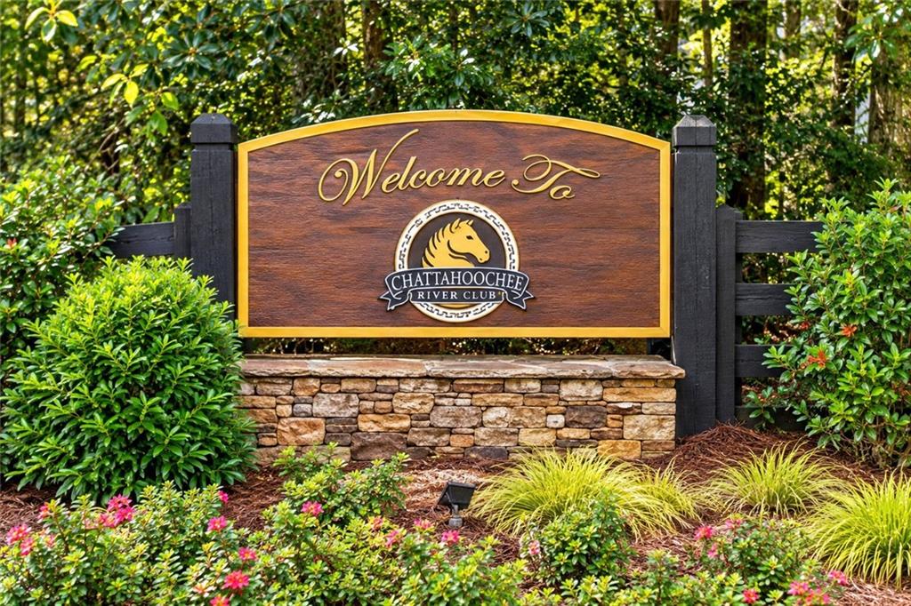 Chattahoochee River Club entrance sign surrounded by flowering shrubs and greenery.