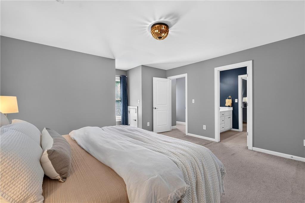 Furnished bedroom with a low bed, gray walls, and an adjoining bathroom doorway.