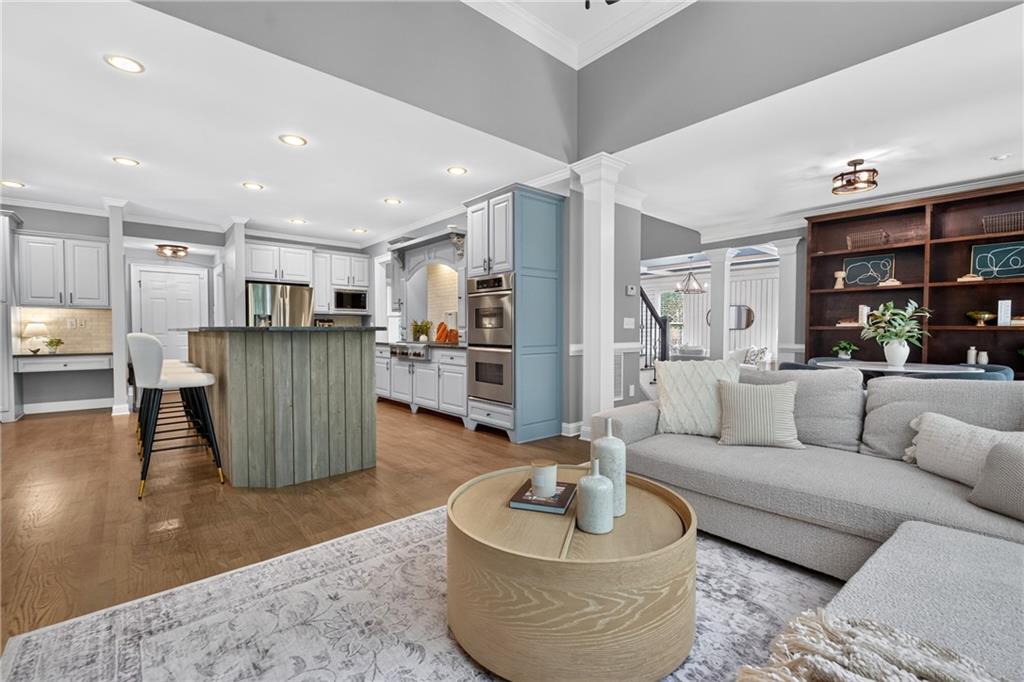 Open-plan kitchen and living room with a blue island, gray cabinets, and a large sectional sofa.