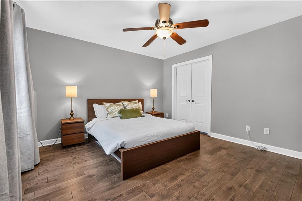 Bedroom with a dark wood bed, gray walls, wood-look floors, and a ceiling fan.