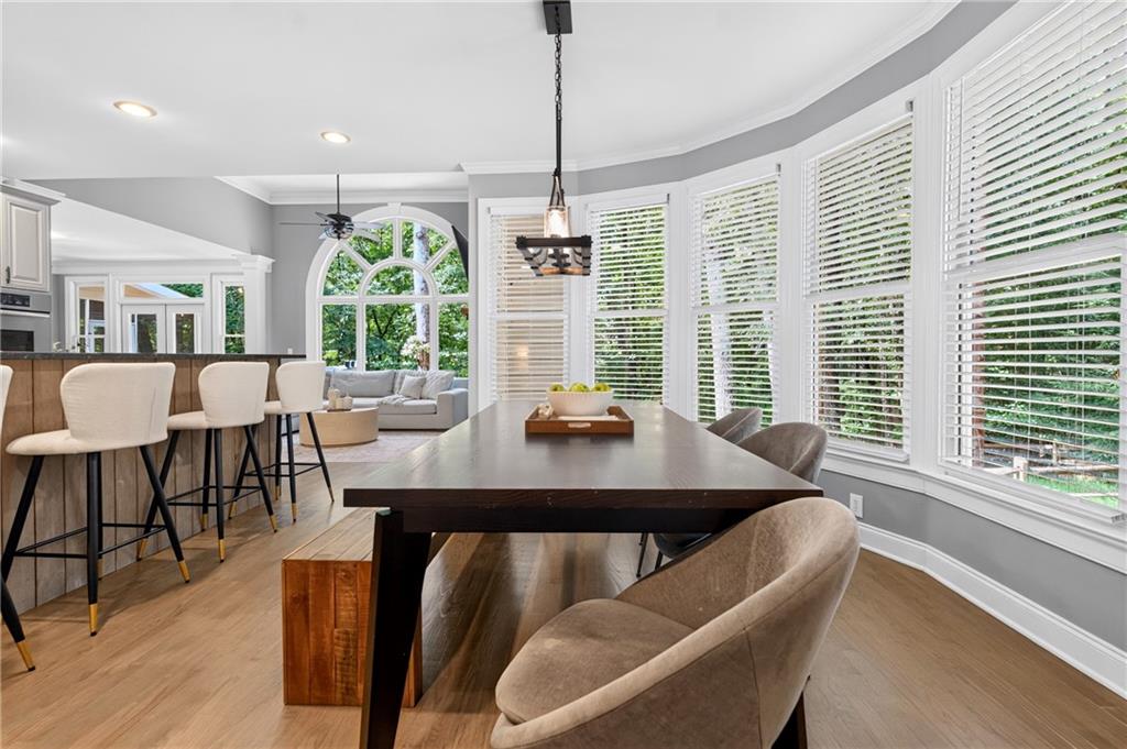 Dining area with dark table and upholstered chairs beside bright kitchen and living room.