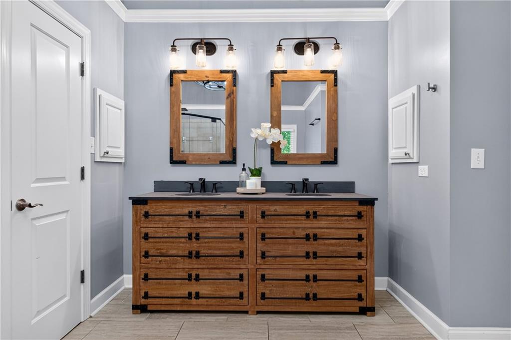 Bathroom with a wooden double vanity, two sinks, and matching framed mirrors.