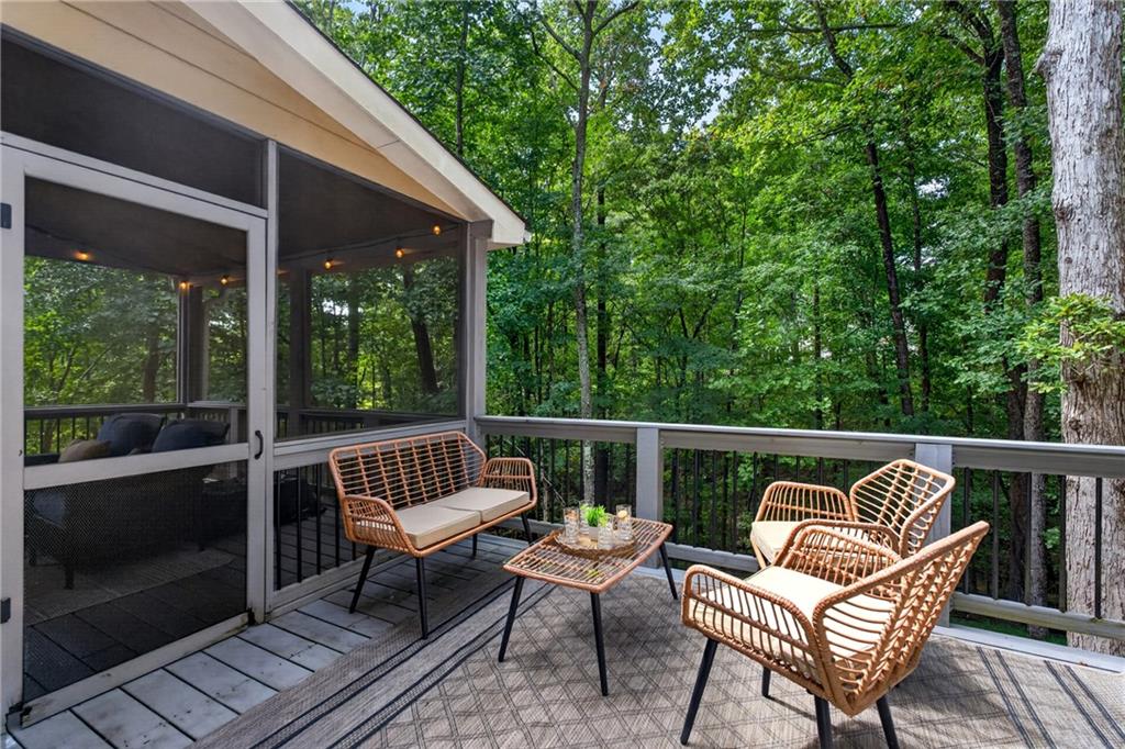 Furnished deck with wicker seating overlooking a wooded backyard.