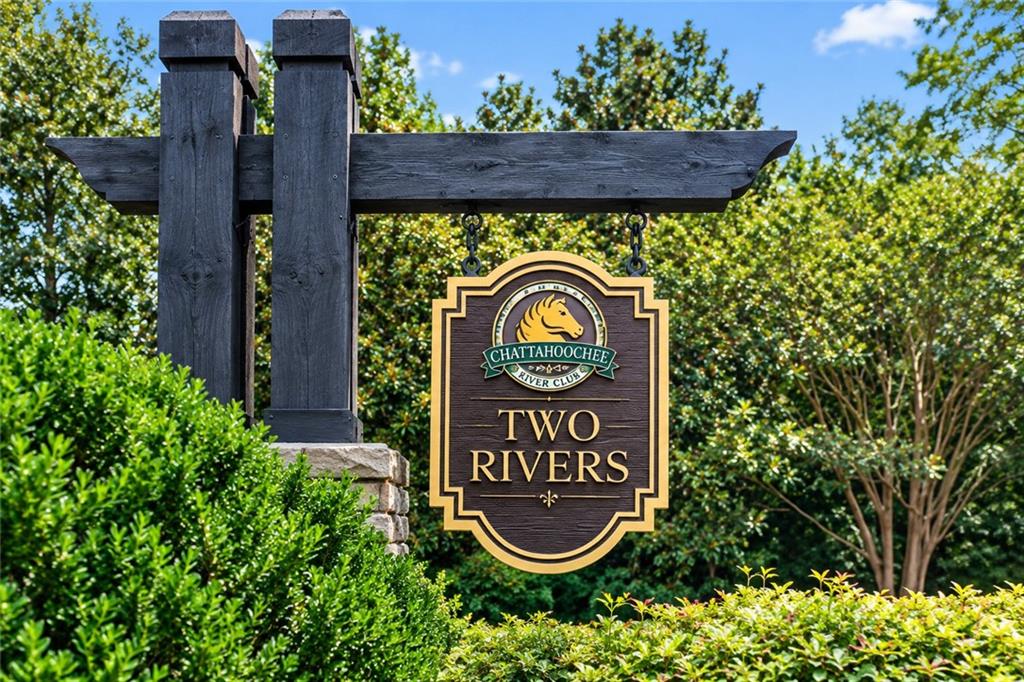 Two Rivers community entrance sign for Chattahoochee River Club, framed by lush shrubs and trees.