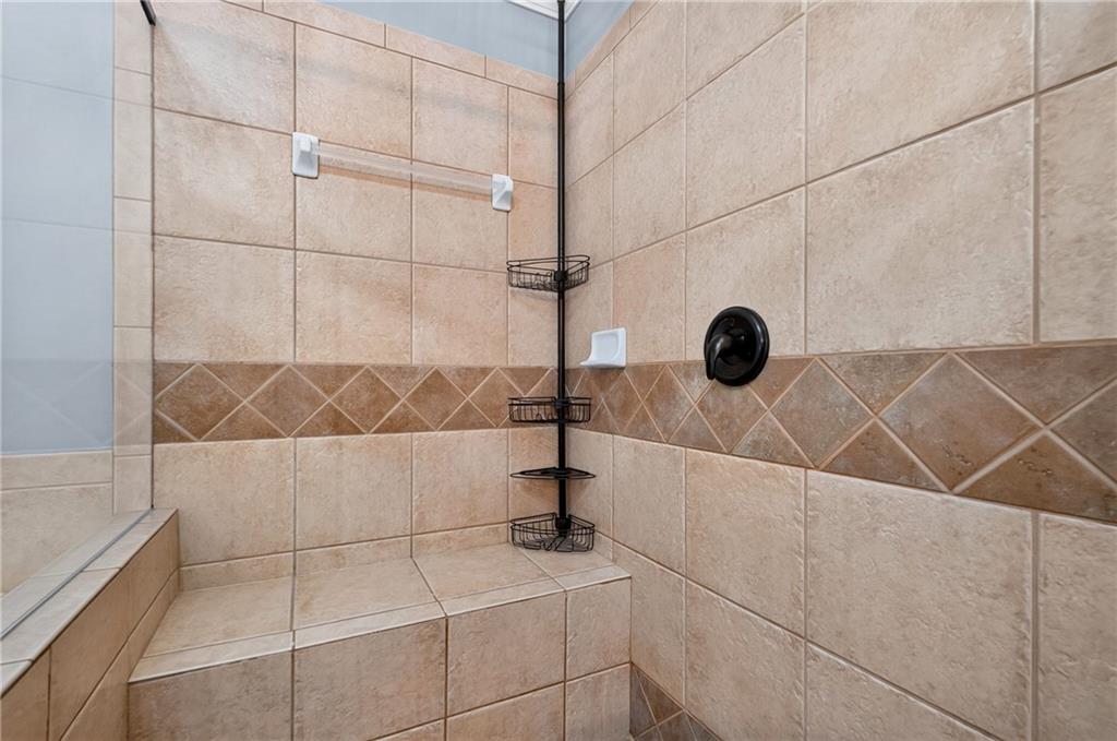 Tiled shower with a built-in bench, glass enclosure, and corner wire shelves.