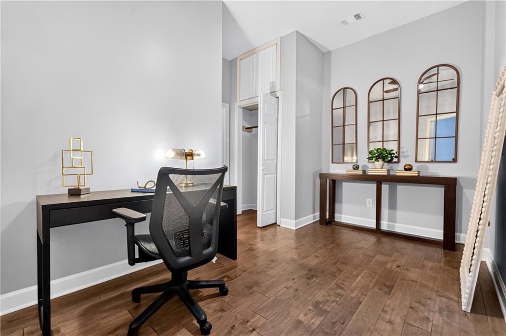 Home office with a black desk, mesh chair, and console table beneath three arched mirrors.