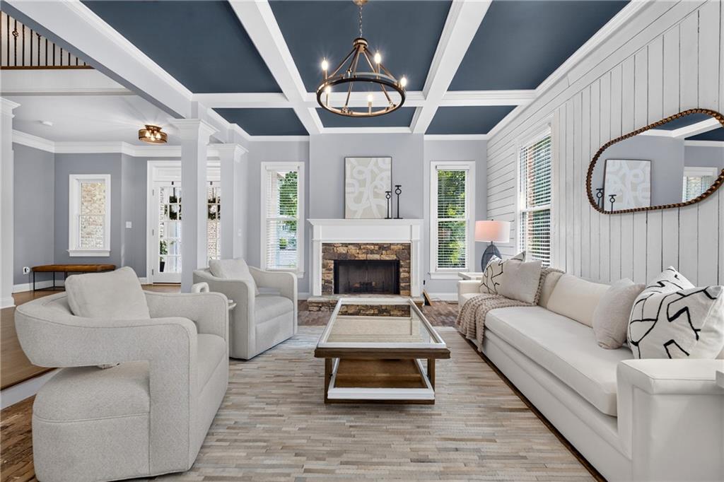 Living room with a coffered ceiling, white seating, and a stone fireplace.