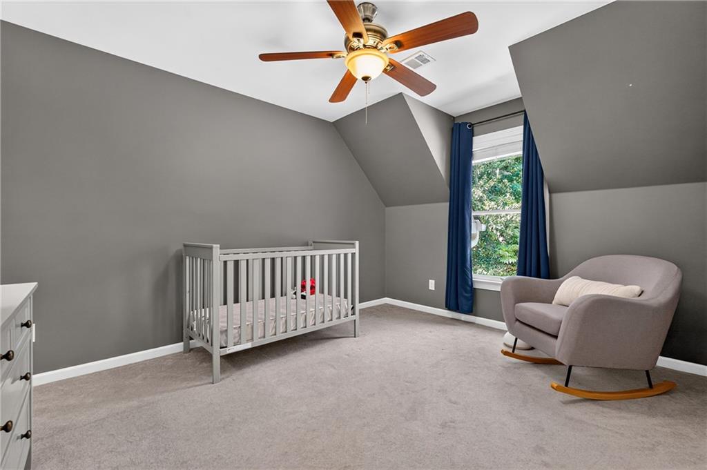 Nursery with a white crib, upholstered rocking chair, and navy curtains framing the window.