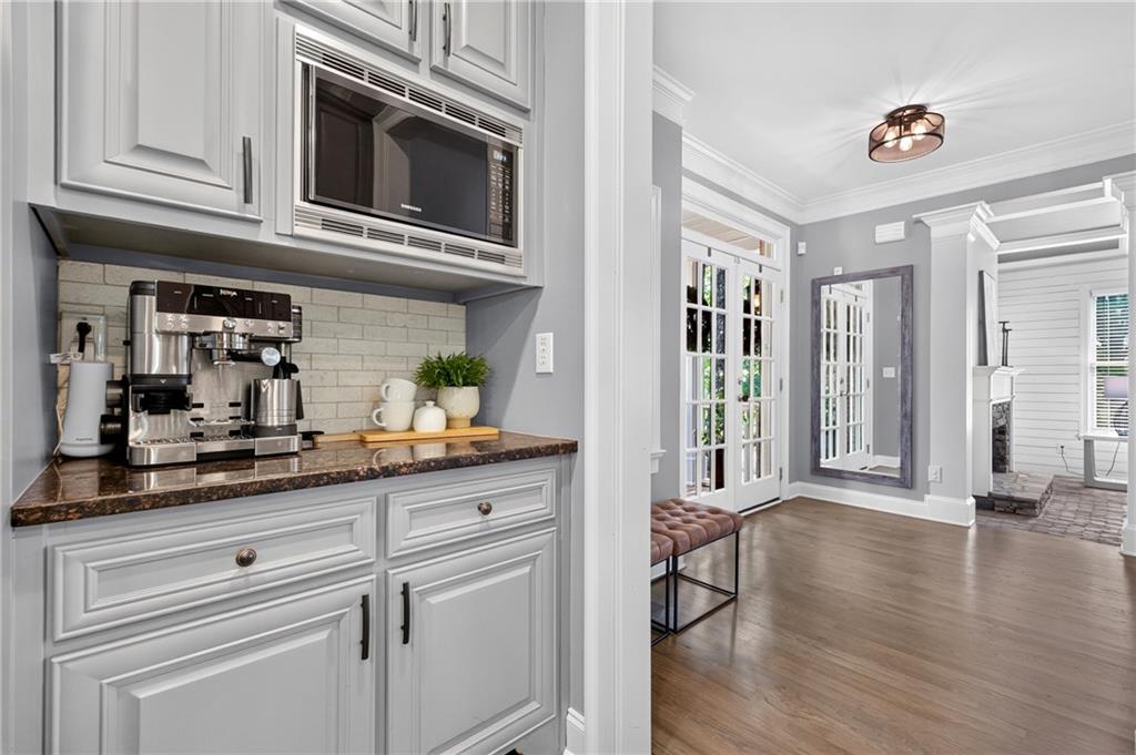 Kitchen coffee station with an espresso machine beside an entry with French doors and a wall mirror.
