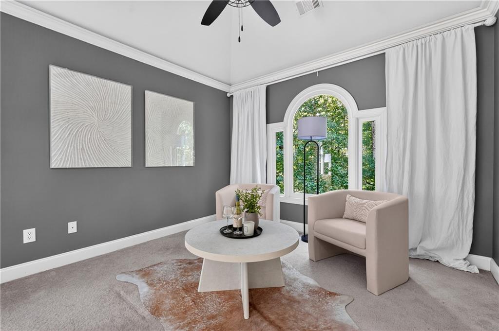 Staged sitting area with pale armchairs and a round coffee table beside an arched window.