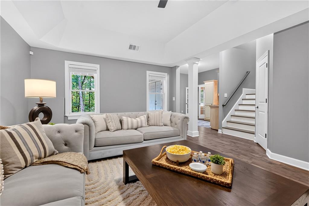 Staged living room with gray tufted sofas, a dark coffee table, and an open staircase.