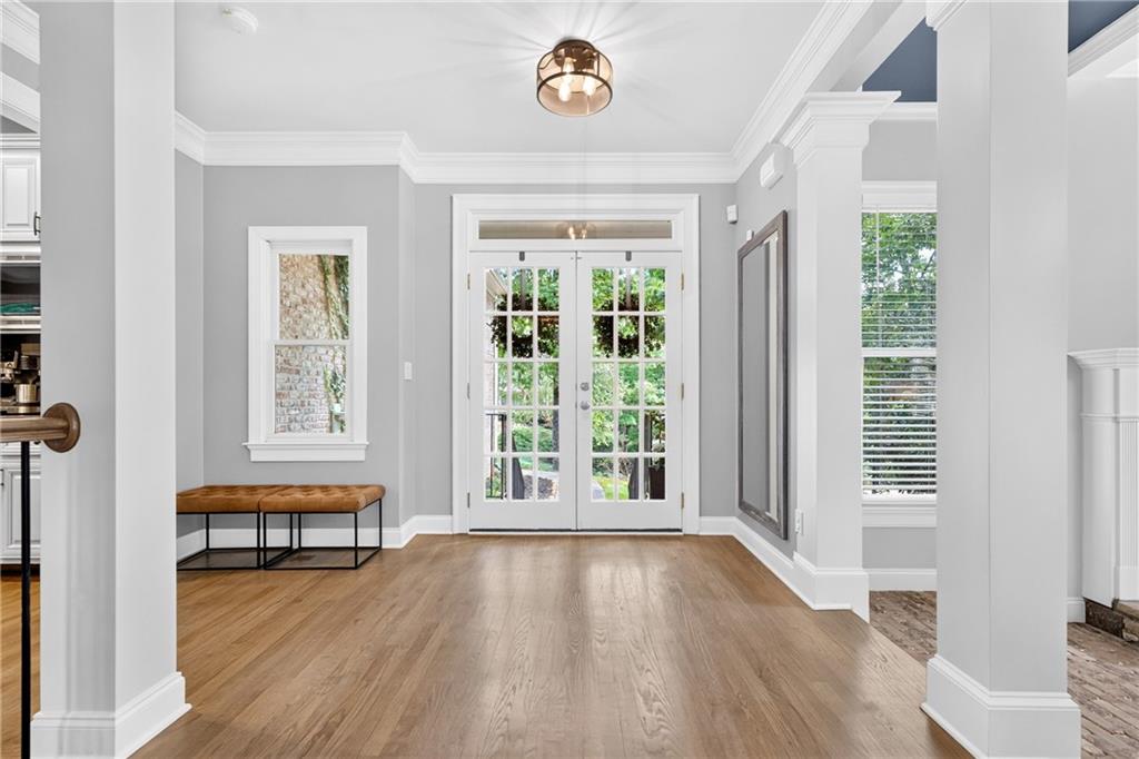 Entry foyer with hardwood floors, French doors, and a bench beneath the window.